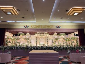 Wedding decor for a reception stage with blush pink florals and crystal chandeliers in a banquet hall