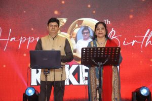Singers performing on stage with microphones at Rakesh’s 60th birthday celebration