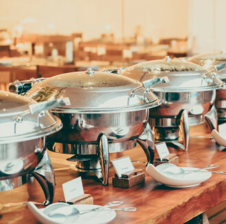 Row of covered chafing dishes on a wedding catering buffet table