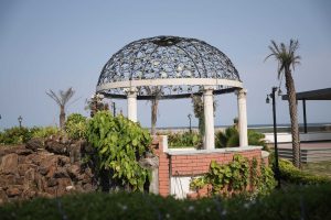 Outdoor wedding venue with a white gazebo in a seaside garden lined with palm trees