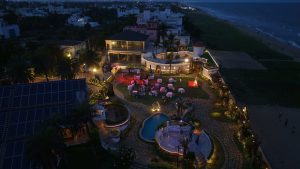 Aerial night view of a beachside wedding venue with a lit reception lawn by the sea