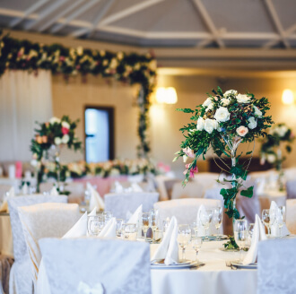 Banquet wedding venue with round tables, white linen and floral centrepieces