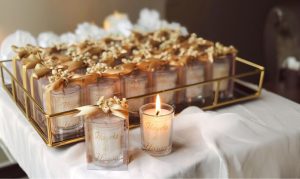 Candle wedding favours tied with gold ribbon on a serving tray