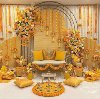 Haldi stage decoration with marigold garlands, yellow cushions and a floral arch